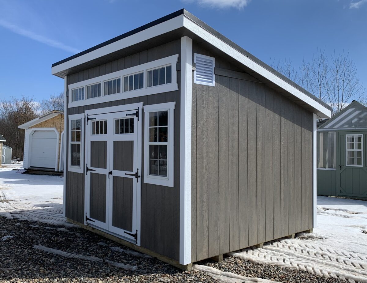 10x12 Studio style storage shed with brown metal roof and stained wood siding on display in Berlin, CT.