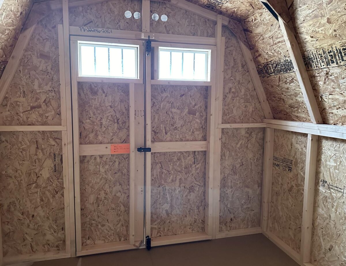 Shed double doors with transom windows and black hardware on a mini barn.