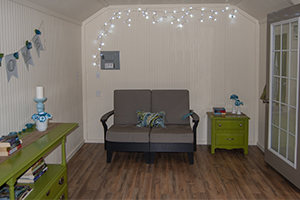Custom Home Office Building from Pine Creek Structures | Finished Shed Interior with painted beadboard walls, electrical package, other custom upgrades, and decorations