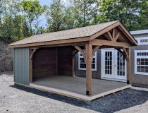 12x20 cabana with six foot, three sided enclosure. Appears rustic with its 6x6 rough-cut hemlock posts stained a deep smokey brown. The forest gren vinyl board and batten siding adds to the rustic charm; as does the rough-cut hemlock interior