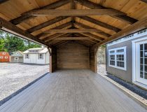 Looking into a 12x20 cabana with six foot, three sided enclosure. Appears rustic with its 6x6 rough-cut hemlock posts stained a deep smokey brown. The rough-cut hemlock interior adds to the rustic charm.