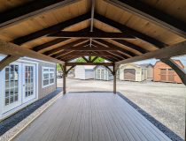 Looking out from inside a 12x20 cabana with six foot, three sided enclosure. Appears rustic with its 6x6 rough-cut hemlock posts stained a deep smokey brown. The rough-cut hemlock interior adds to the rustic charm.