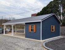 Side view of a 20×36 Veranda Cabana featuring blue siding, white trim, wood shutters, and an extended covered patio area supported by decorative columns.