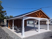 20x26 cabana with a metal roof, white vinyl posts, wooden siding, and two porch swings hanging in the open pavilion area.