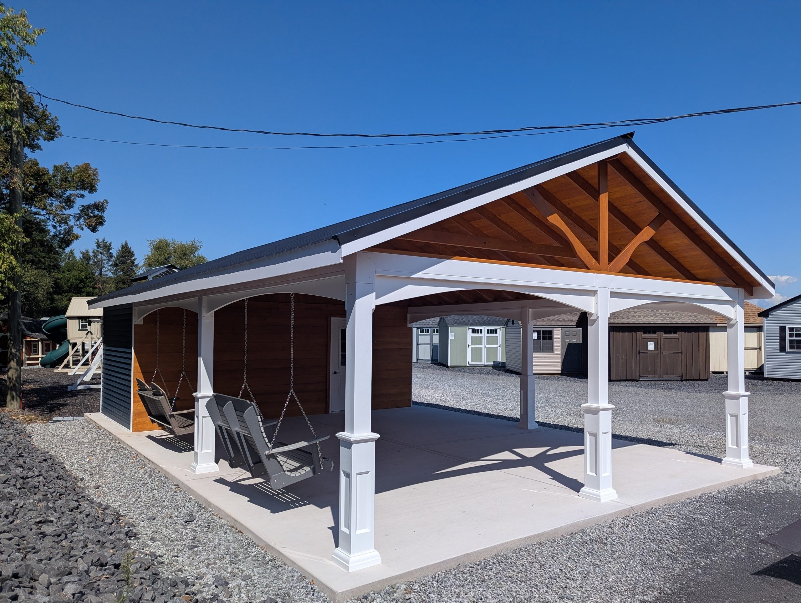 20x26 cabana with a metal roof, white vinyl posts, wooden siding, and two porch swings hanging in the open pavilion area.