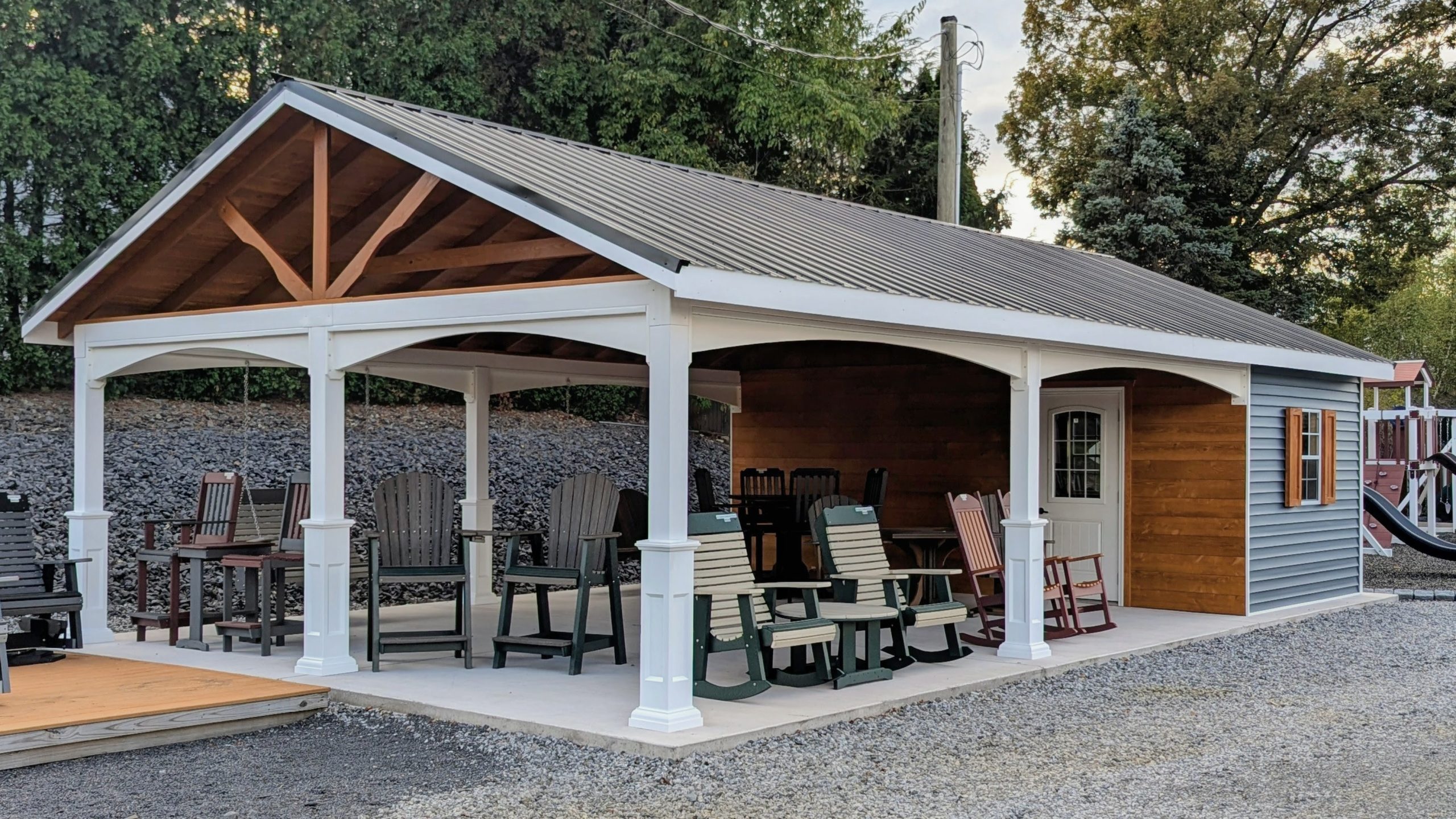 20x26 cabana with metal roof and open pavilion space, furnished with outdoor chairs and tables, attached to an enclosed wooden room with window and shutters.