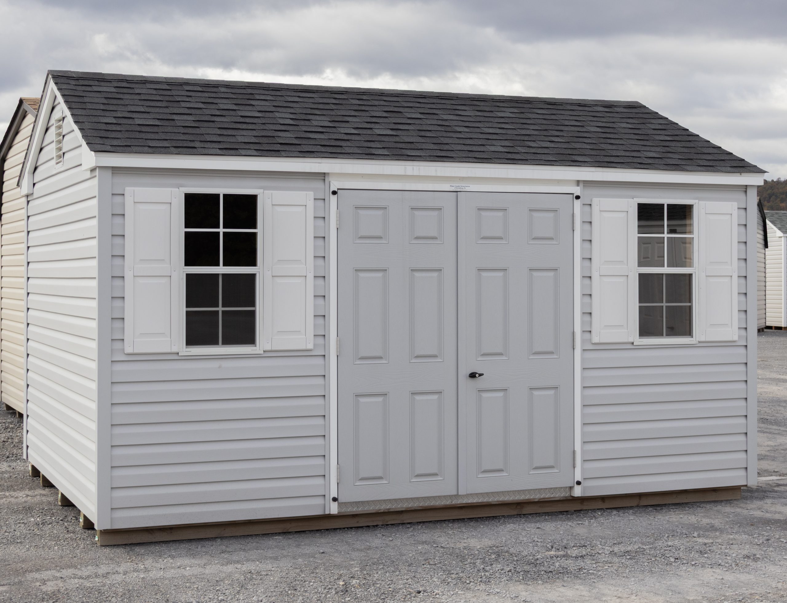 10x14 Peak Style Storage Shed with Harbor Stone Grey Vinyl Siding, a double door, and two single hung windows with shutters