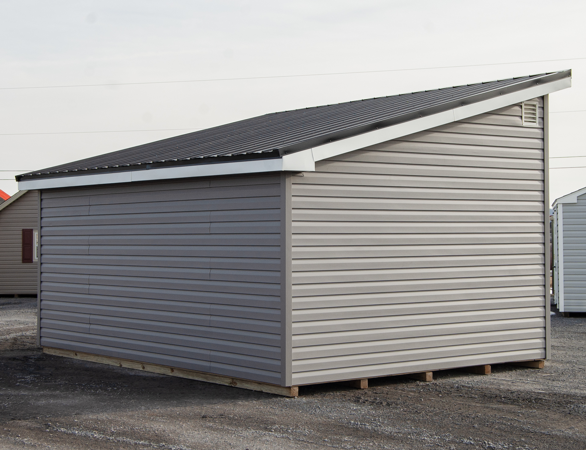 12x16 Studio Style Storage Shed with many windows and graphite grey vinyl siding and metal roof