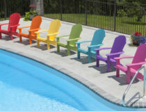 A rainbow of Adirondack Chairs by a pool
