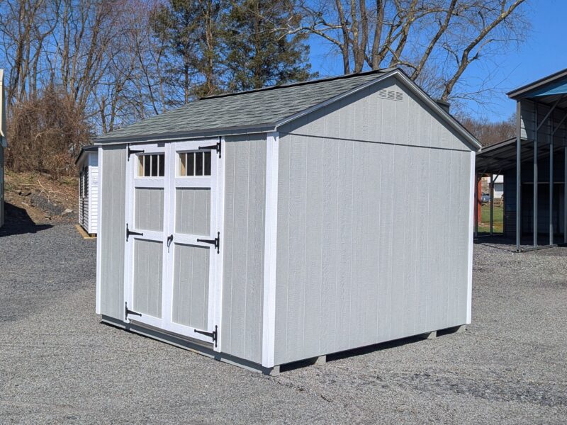 10×10 Madison Peak shed with light gray LP SmartSide siding, white trim, and shadow gray shingles, featuring double barn doors with transom windows and black hardware, displayed on a gravel lot.