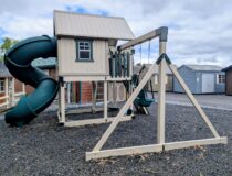 Vinyl playset with clubhouse, enclosed tube slide, and bucket swing on rubber mulch