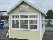 Interior of an 8x12 atrium greenhouse featuring two built-in grating benches for potting plants.