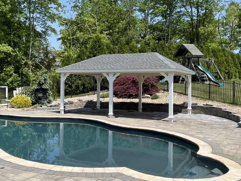 Custom Amish built 14x20 hip pavilion with white vinyl trim and black architectural shingles in a backyard patio setting.