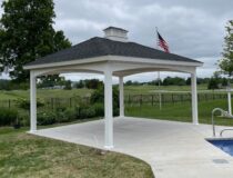 White 14x14 hip style pavilion with arched headers next to a swimming pool