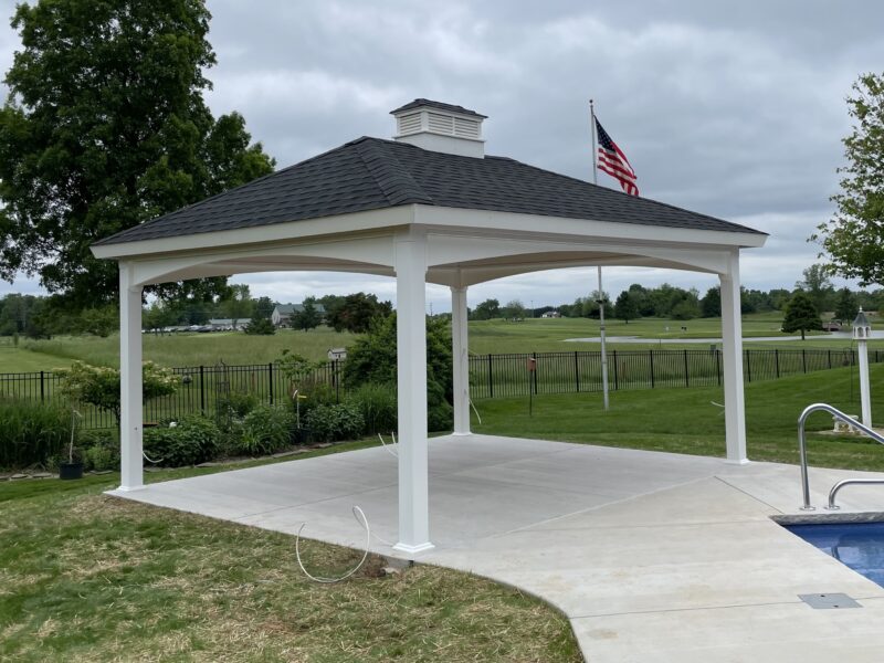 White 14x14 hip style pavilion with arched headers next to a swimming pool