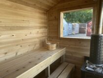 Interior of an 8x12 outdoor sauna featuring multi-level solid white cedar benches and an off-grid LED lighting system.