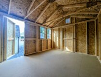 Interior of 10x12 Economy Peak shed with wood framing, windows, double doors, and storage loft