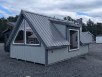 Side view of 12x20 A-frame cabin with triangular windows, metal roof, and large picture window