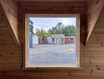 Large picture window inside finished 12x20 A-frame cabin with knotty pine walls