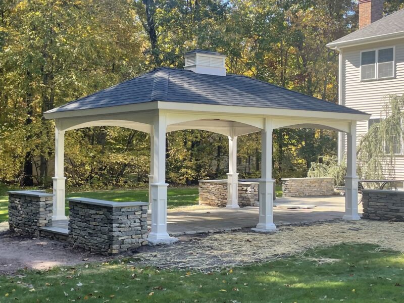 14x18 white vinyl hip roof pavilion installed over a backyard patio by Pine Creek Structures